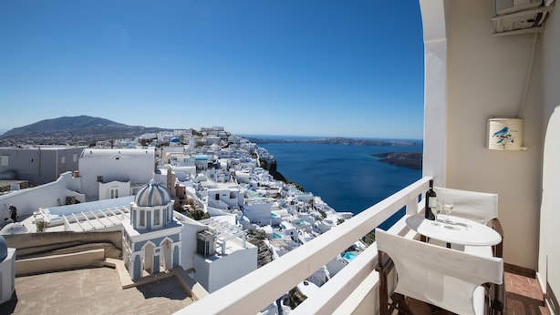 A balcony with a view of a coastal town, white buildings, and a clear blue sky. - Villa Ilias Caldera Hotel (Santorini)