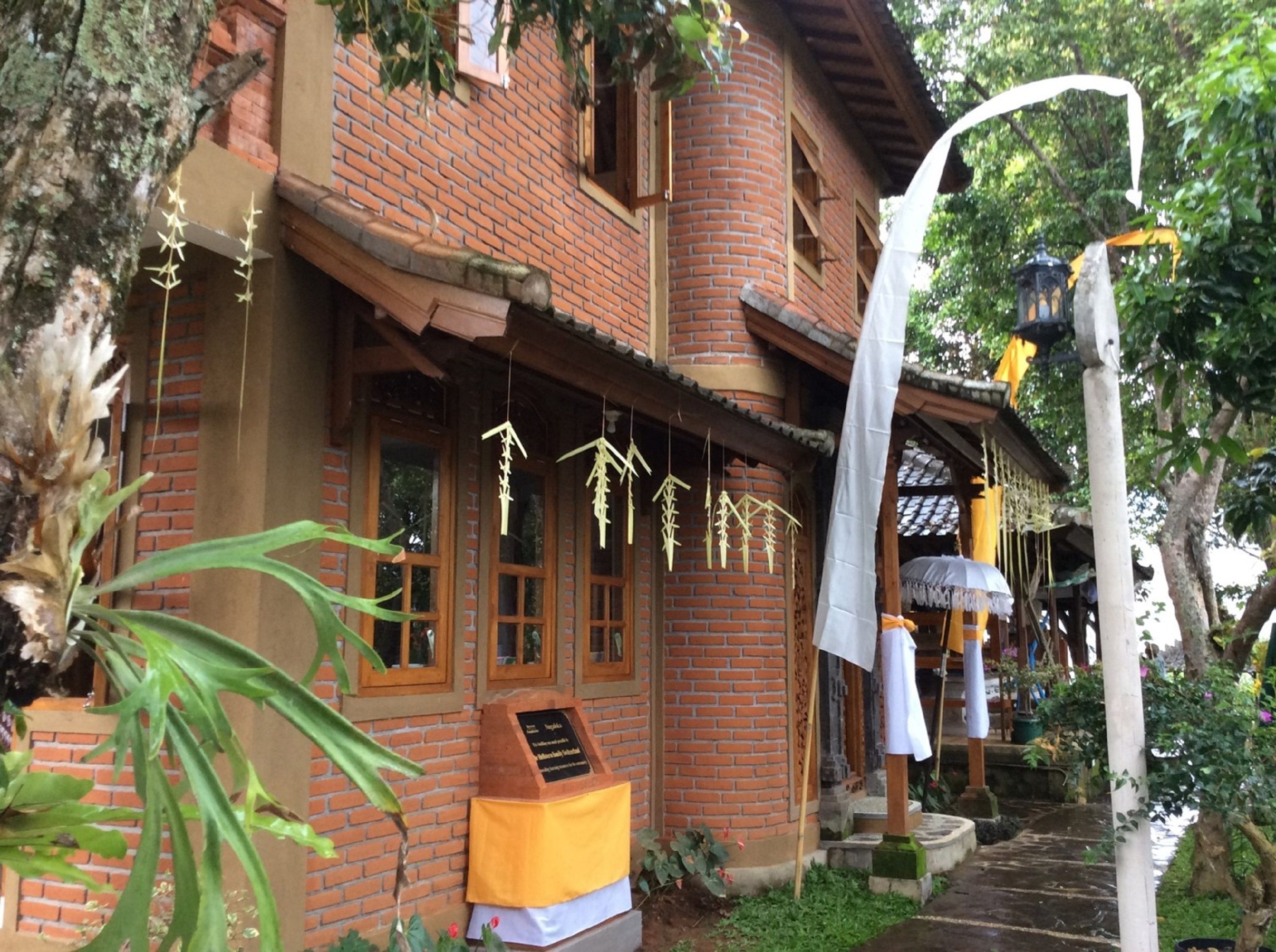A traditional brick building with a wooden porch, hanging decorations, and a lantern.
