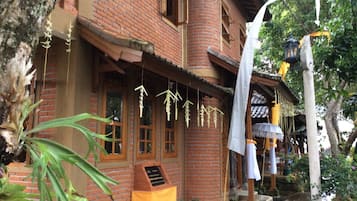 A traditional brick building with a wooden porch, hanging decorations, and a lantern.