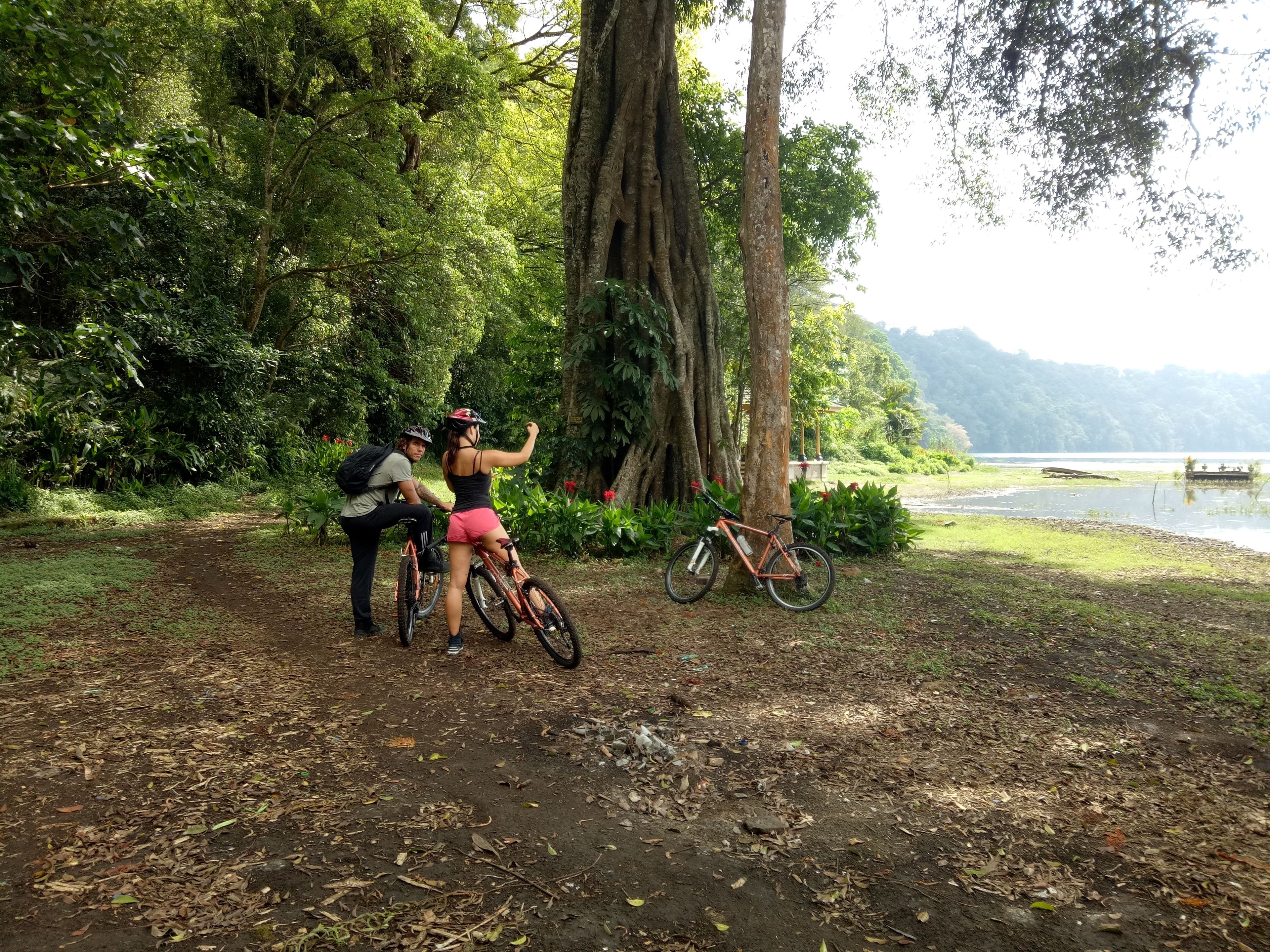 A natural setting with a dirt path, a bicycle, and a lake in the background.