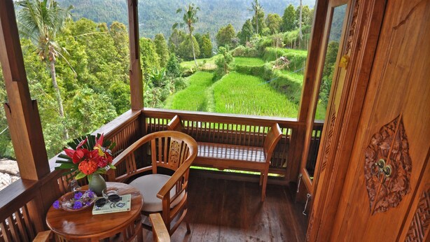 A wooden deck with a bench and table, overlooking lush green rice terraces. - Puri Lumbung Cottages, Restaurant & Spa (Munduk)