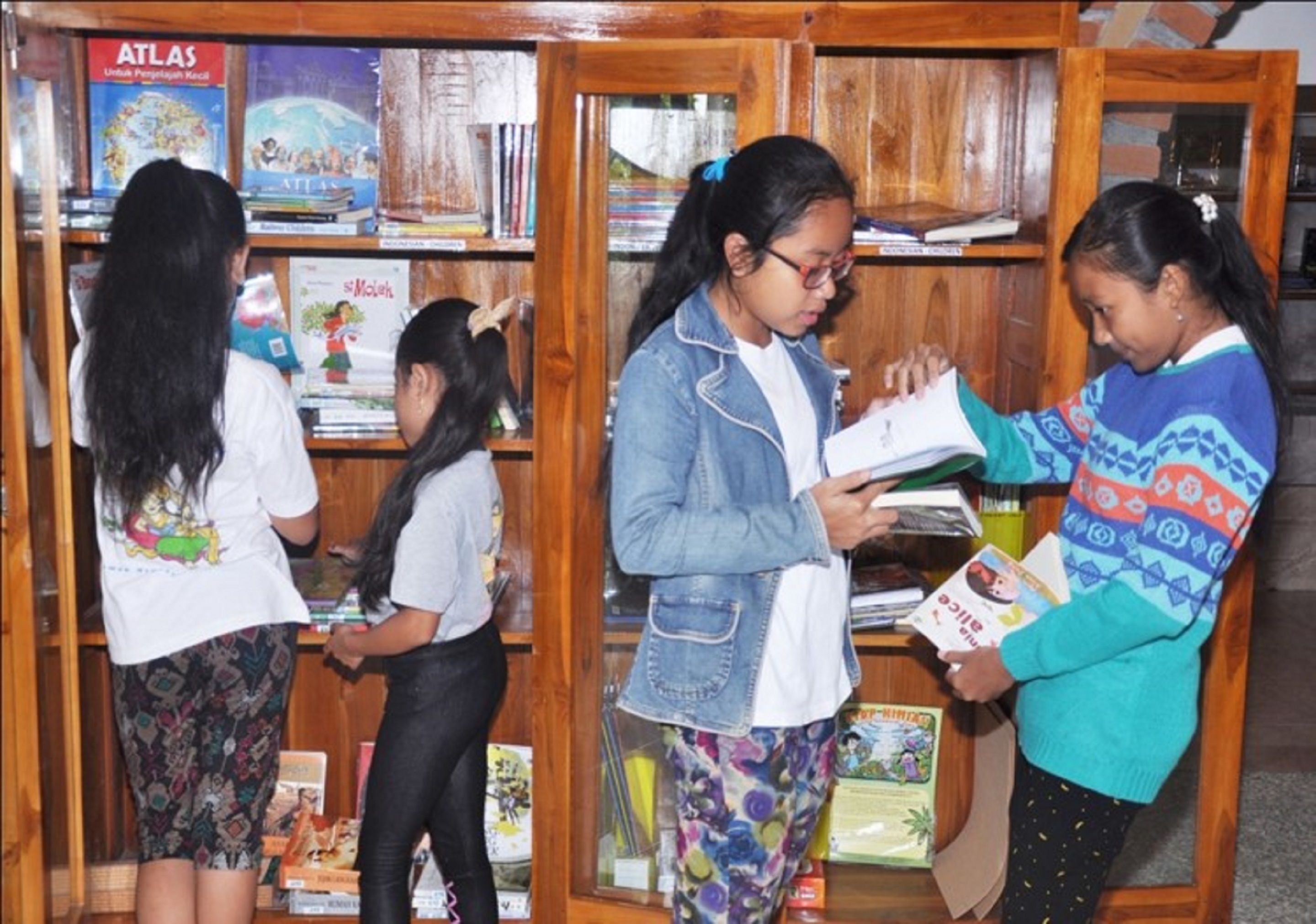 A group of people in a library with wooden bookshelves filled with books.