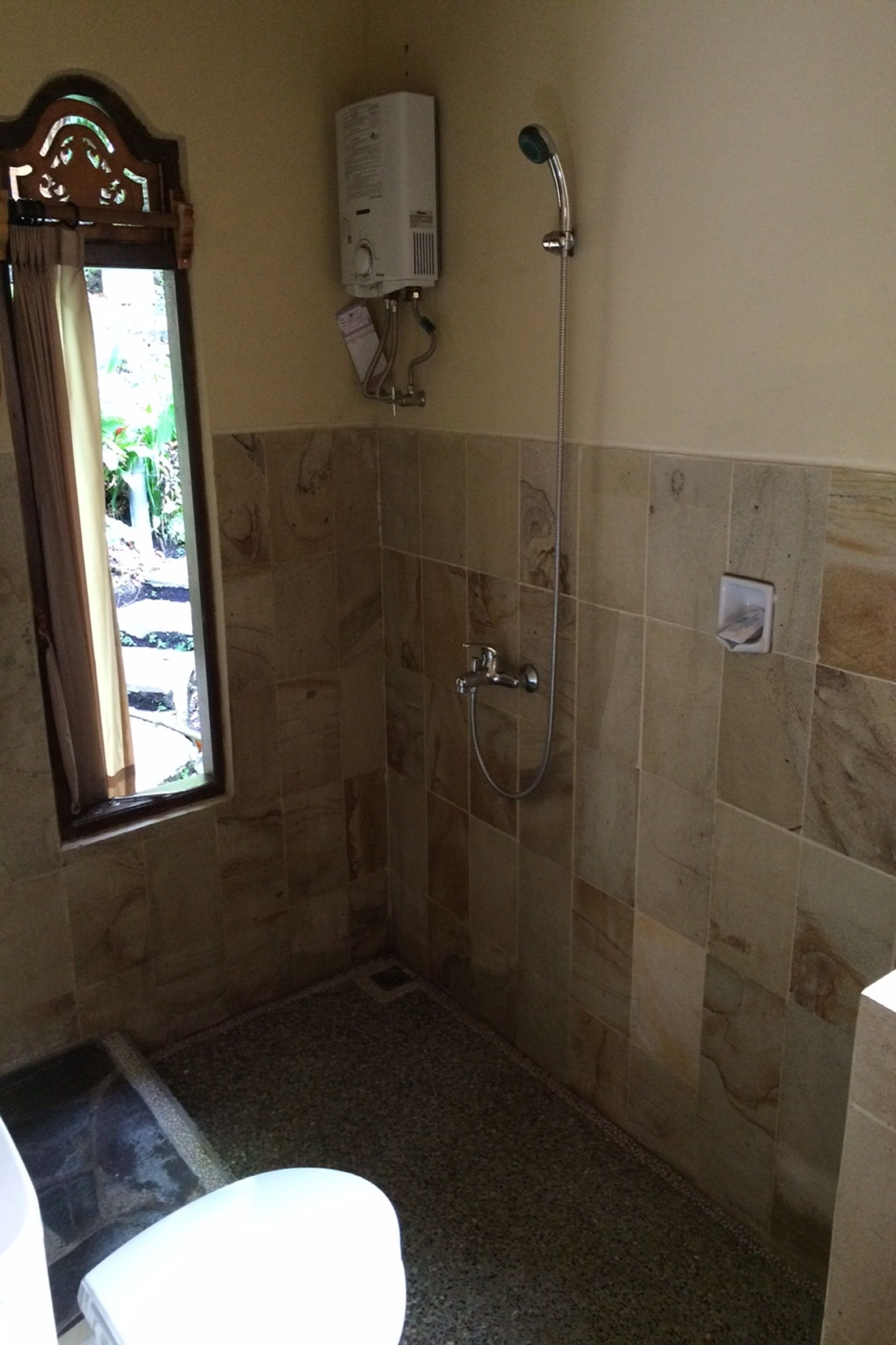 Une salle de bain avec une douche, des toilettes et une fenêtre.