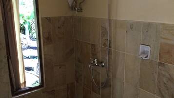 Une salle de bain avec une douche, des toilettes et une fenêtre.