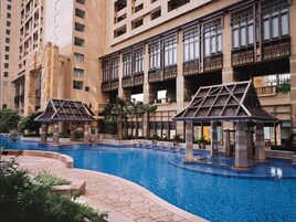 Una piscina con dos gazebos, rodeada de edificios altos con balcones y ventanas amplias.