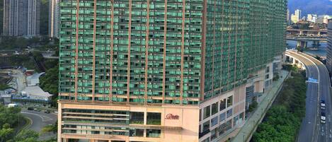 Un hotel moderno de gran altura, con varios pisos, una entrada destacada y un entorno urbano circundante con calles y otros edificios.
