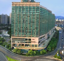 Un hotel moderno de gran altura, con varios pisos, una entrada destacada y un entorno urbano circundante con calles y otros edificios.