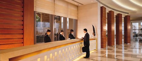 Ein Hotel-Rezeptionsbereich im modernen Design mit Empfangsschalter, Wartebereich und Check-in-Theke.