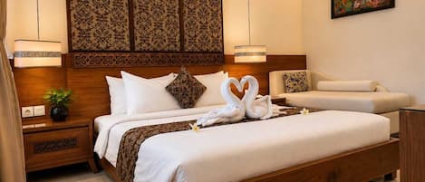 A hotel room with a large bed, a wooden headboard, a decorative panel, a sofa, and a painting on the wall.