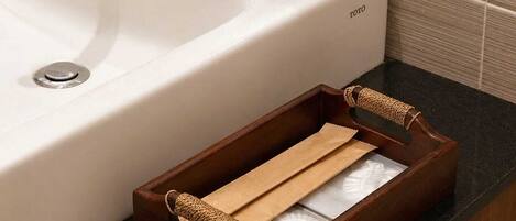 A bathroom sink with a wooden soap dish and a brown tray with handles.