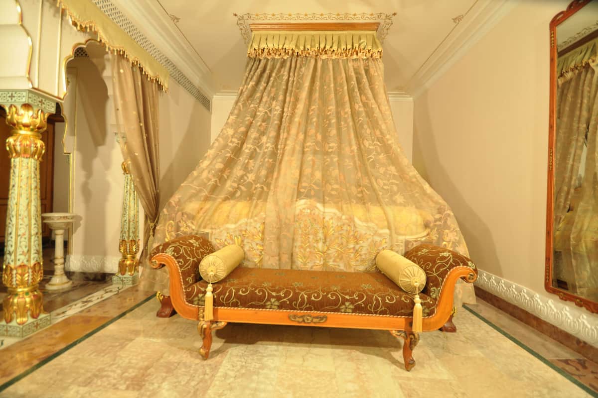 Un dormitorio lujoso con cama con dosel, muebles ornamentados y un espejo en la pared.