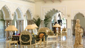 Un lobby lujoso con muebles ornamentados, una estatua y detalles arquitectónicos elaborados.