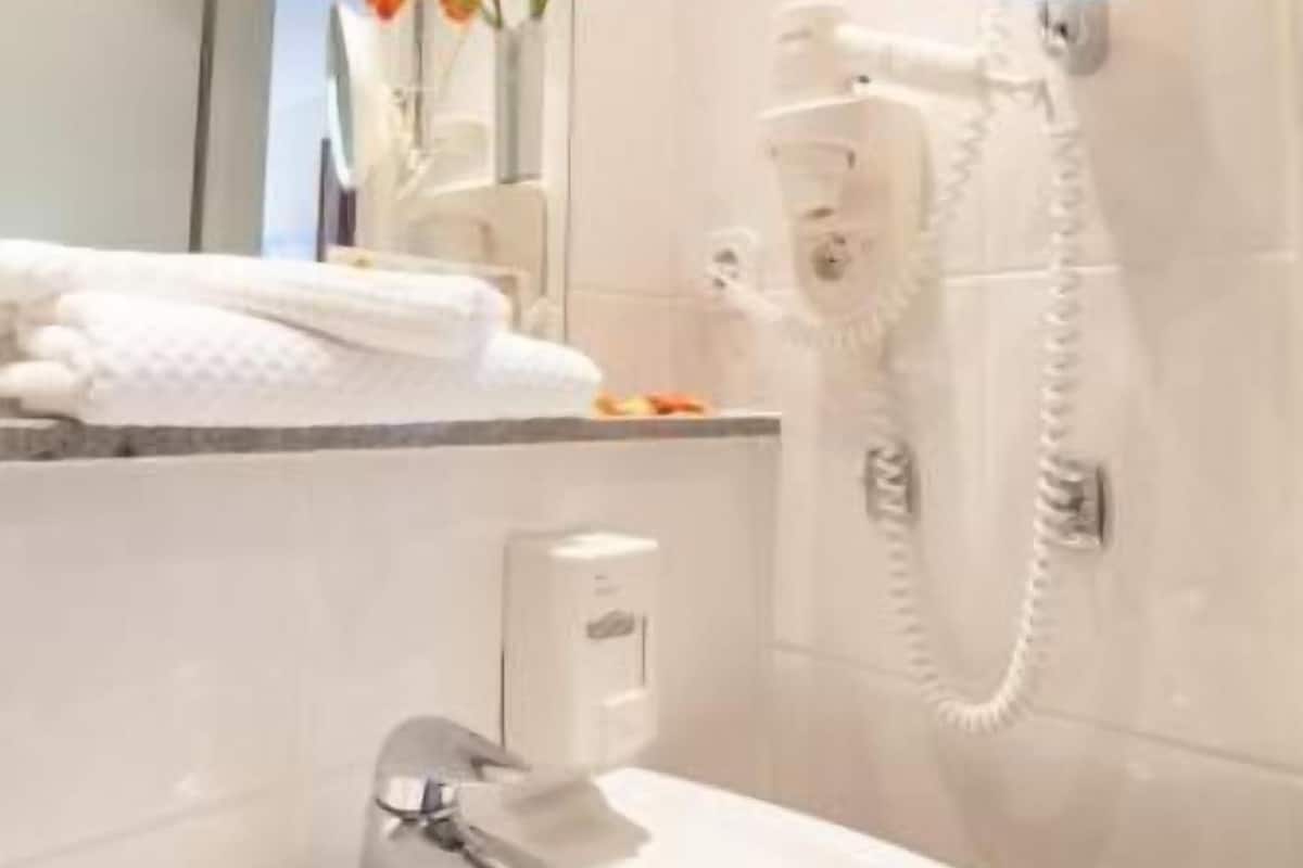 Une salle de bain équipée d’un lavabo, d’un miroir et d’un sèche-cheveux fixé au mur.