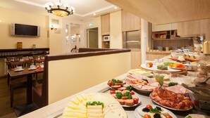 Een buffet met diverse gerechten, waaronder vlees, kaas en groenten.