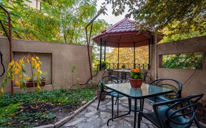 Relax in a serene patio area surrounded by lush greenery and a gazebo, perfect for al fresco dining.