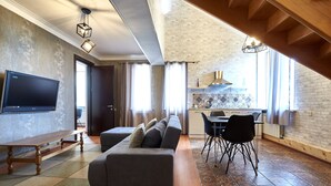 A modern living room with a grey sofa, wooden floor, and a flat-screen TV. - Iliani Hotel (Tbilisi)