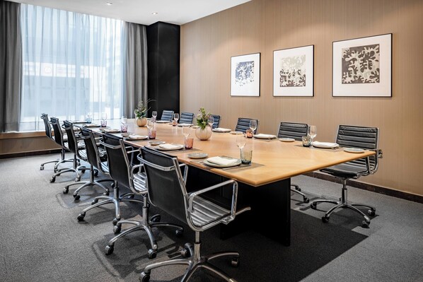 A conference room with a long table, chairs, and framed artwork on the walls.
