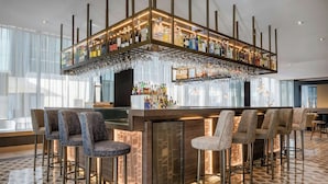 A bar area with multiple stools, a bar counter, and a variety of bottles and glasses.