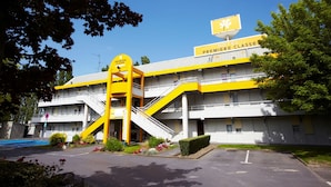 A hotel with a yellow and white exterior, multiple floors, and a prominent staircase. - Premiere Classe Charleville Mezieres (Charleville-Mezieres)