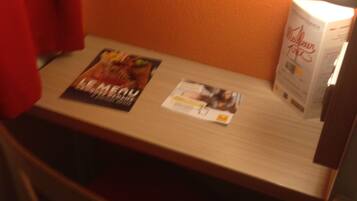 A hotel room with a wooden table, a chair, a lamp, and a magazine on the table.
