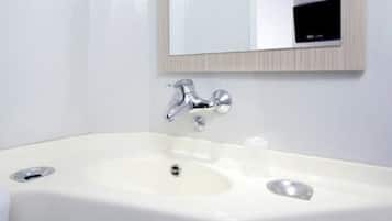 Ein modernes Badezimmer mit einem weißen Waschbecken, einem chromfarbenen Wasserhahn und einem Spiegel darüber.