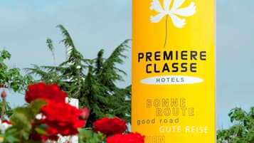A yellow sign with the text "PREMIERE CLASSE HOTELS" and "BONNE ROUTE GUTE REISE" indicating a hotel named Premiere Classe.