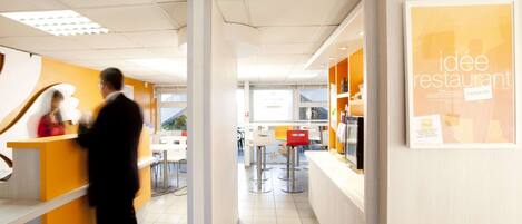 A modern restaurant interior with a reception area, seating, and a counter.