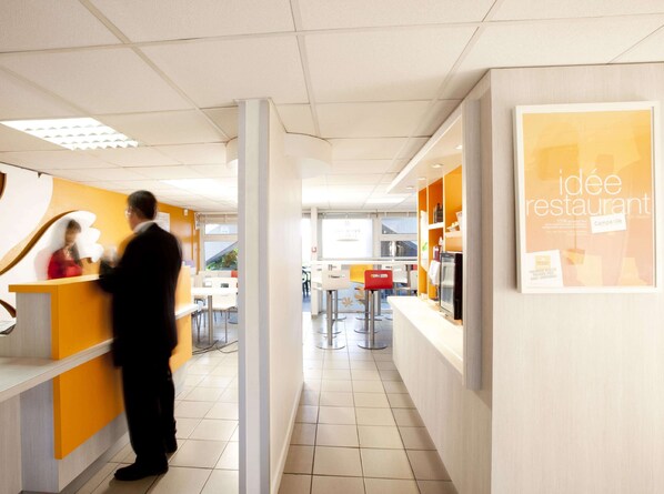 A modern restaurant interior with a reception area, seating, and a counter. - Premiere Classe Caen Est - Mondeville (Mondeville)