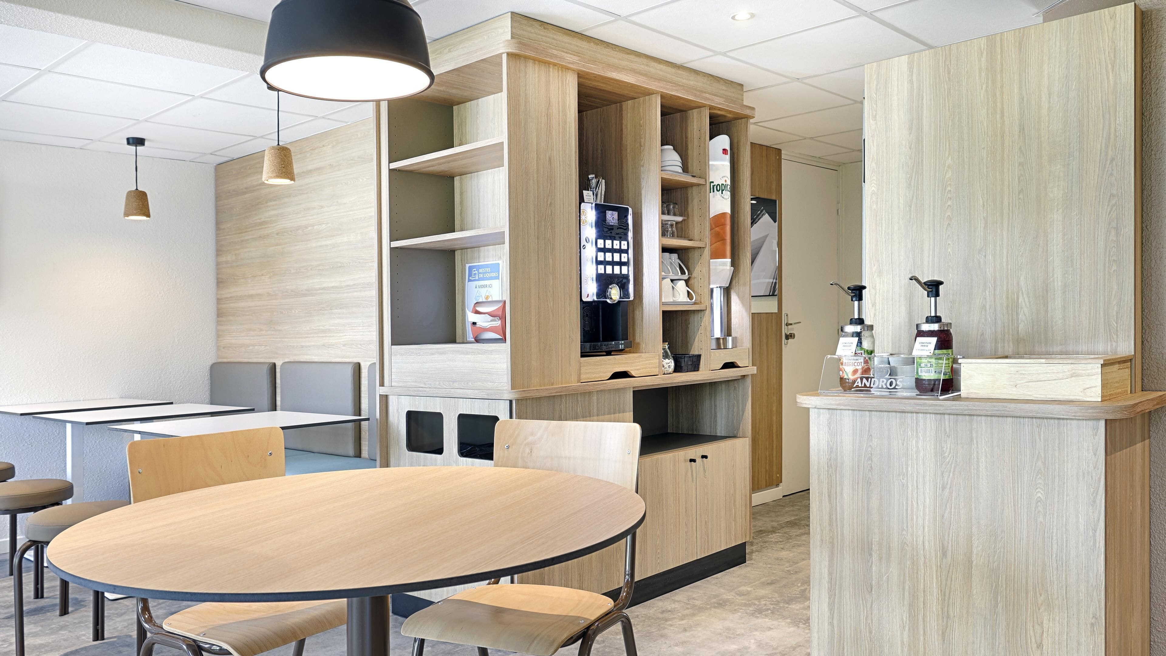 Una cocina moderna con armarios de madera, cafetera integrada y una barra con dispensadores de condimentos.