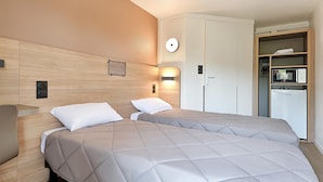 Habitación de hotel con dos camas, un armario, un microondas y un refrigerador.