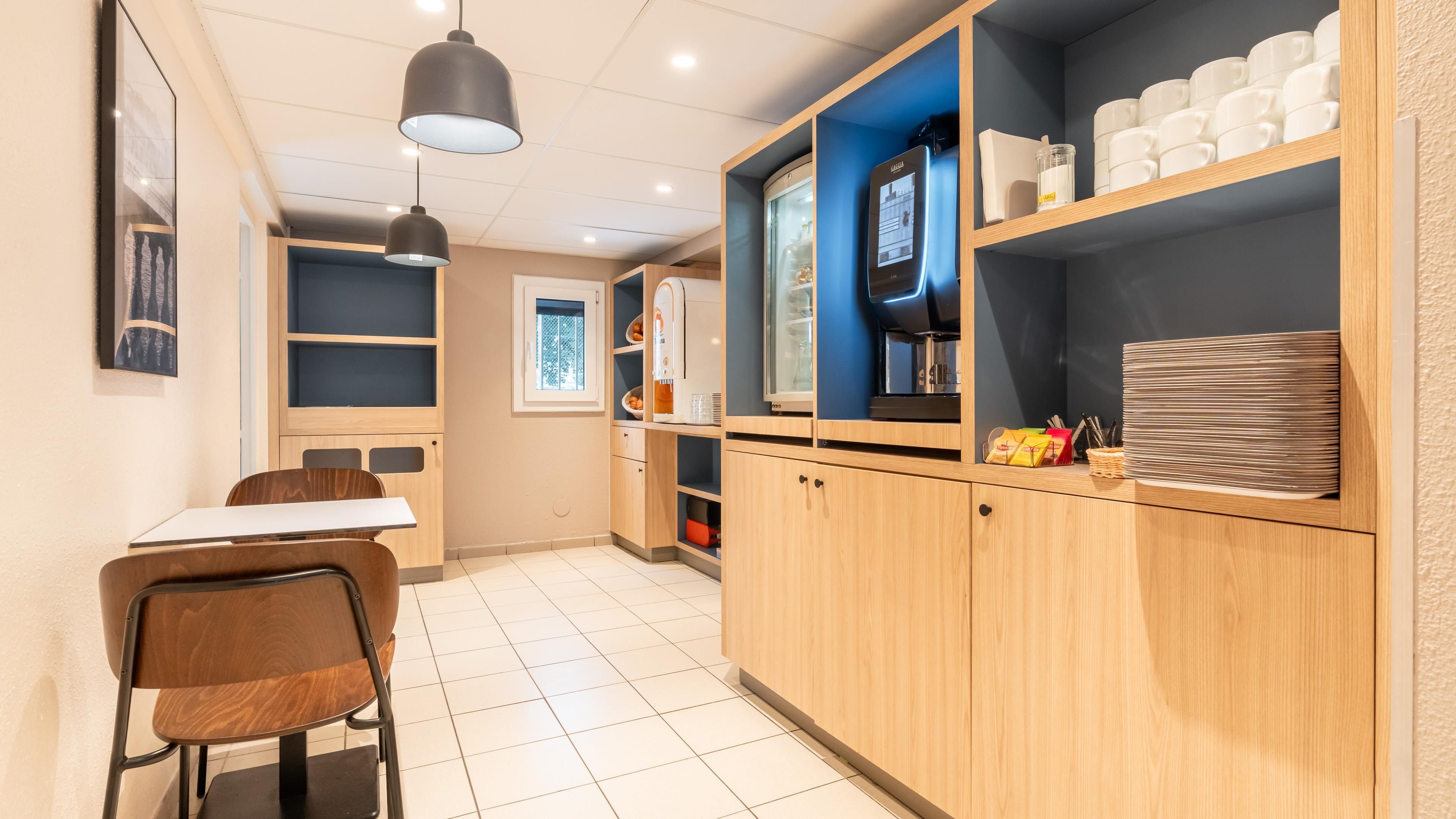 Une cuisine moderne avec un coin repas comprenant une table et des chaises, un réfrigérateur et une machine à café.