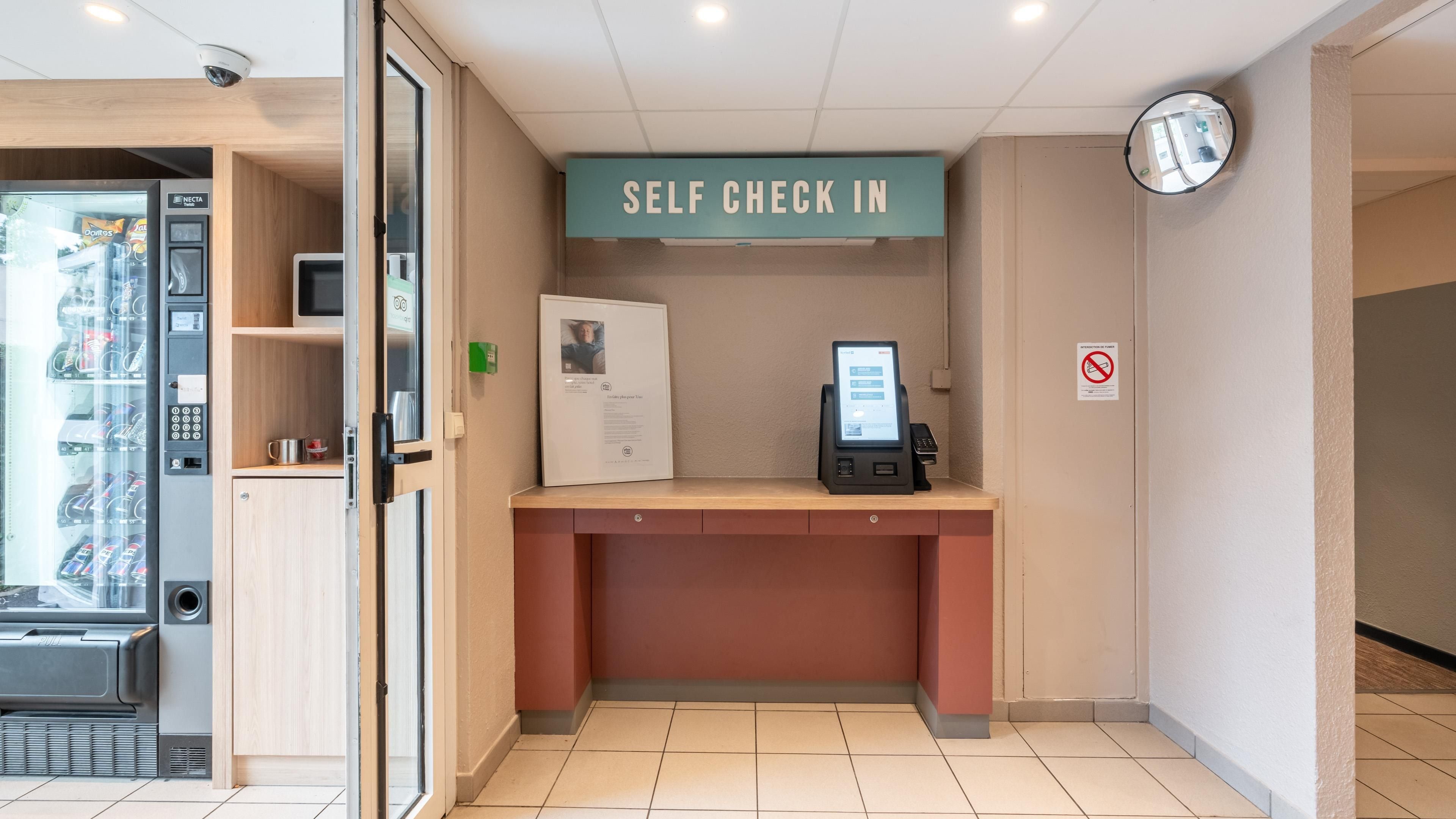 Een zelf incheck automaat met een scherm, een telefoon en een bord erboven.
