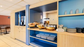 A breakfast buffet area with a coffee machine, bread baskets, and a juice dispenser. - Kyriad ECO - Montreuil (Montreuil)