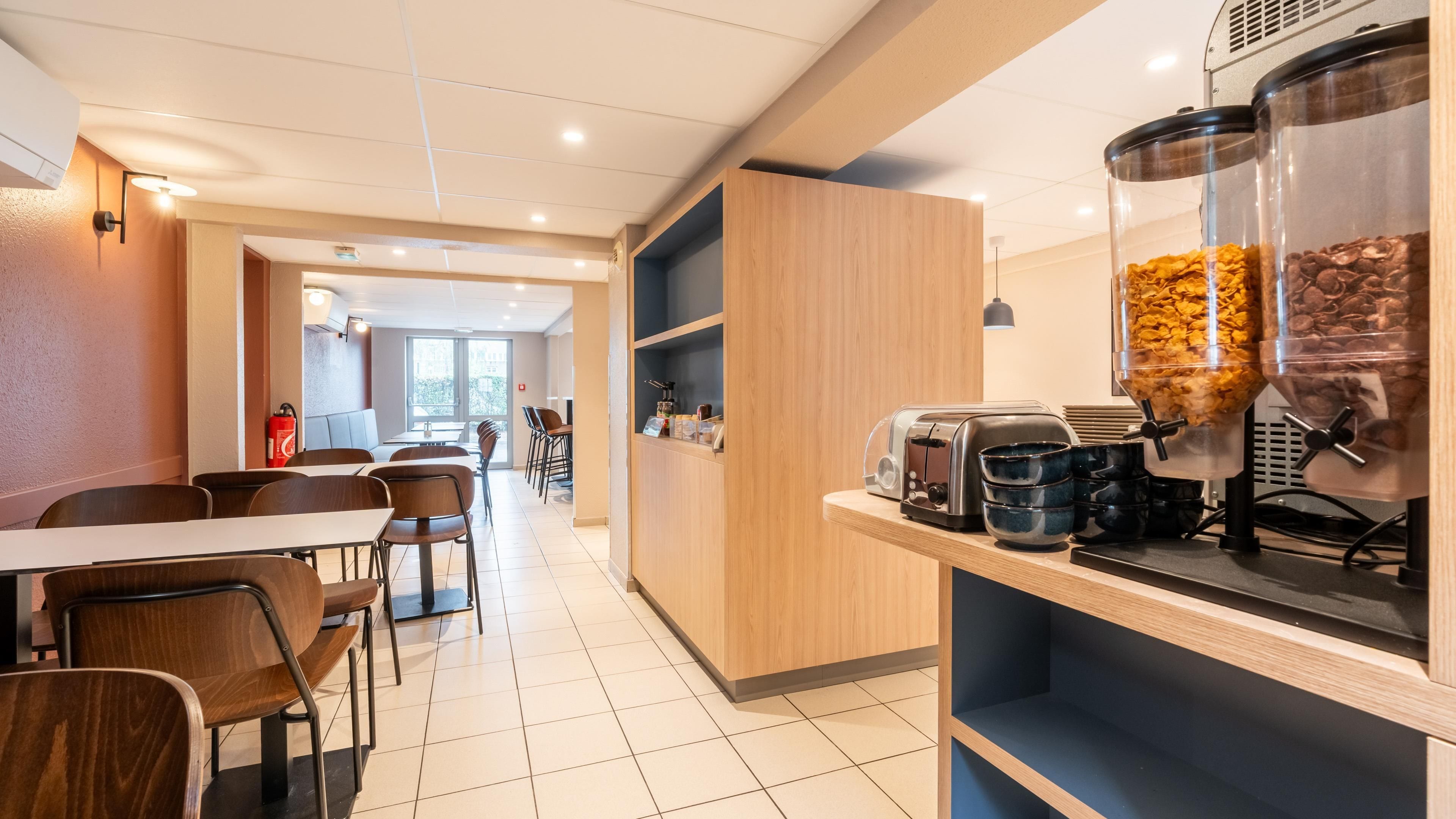 A modern cafe interior with wooden furniture, a coffee machine, and a seating area with tables and chairs.