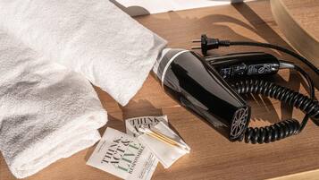 A black hairdryer, a white towel, and a pamphlet on a wooden surface.