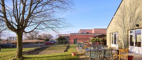 A patio area with outdoor seating, a tree, and a building in the background.