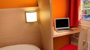 A compact hotel room with a bed, a desk with a laptop, a red chair, and a wall-mounted lamp. - Premiere Classe Reims Sud Bezannes (Reims)