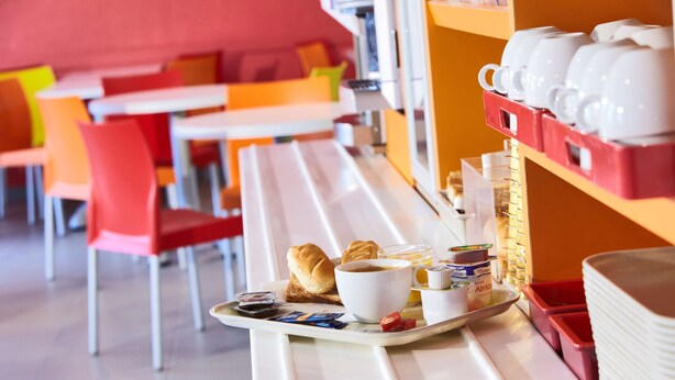 A breakfast tray with croissants, coffee, and jam on a white table in a brightly colored cafe. - Premiere Classe Reims Sud Bezannes (Reims)
