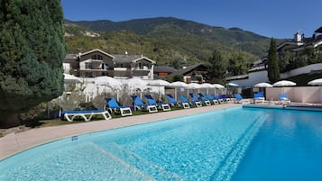 Una piscina al aire libre de temporada, sillones reclinables de piscina