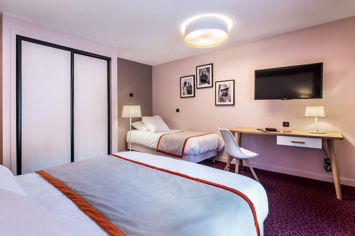 Habitació d'hotel amb un llit gran, un escriptori amb una cadira, una televisió i un armari.