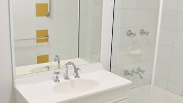 A bathroom with a white sink, two cabinets, a mirror, and a glass-enclosed shower.