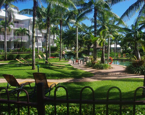 A resort with a pool, palm trees, and lounge chairs.