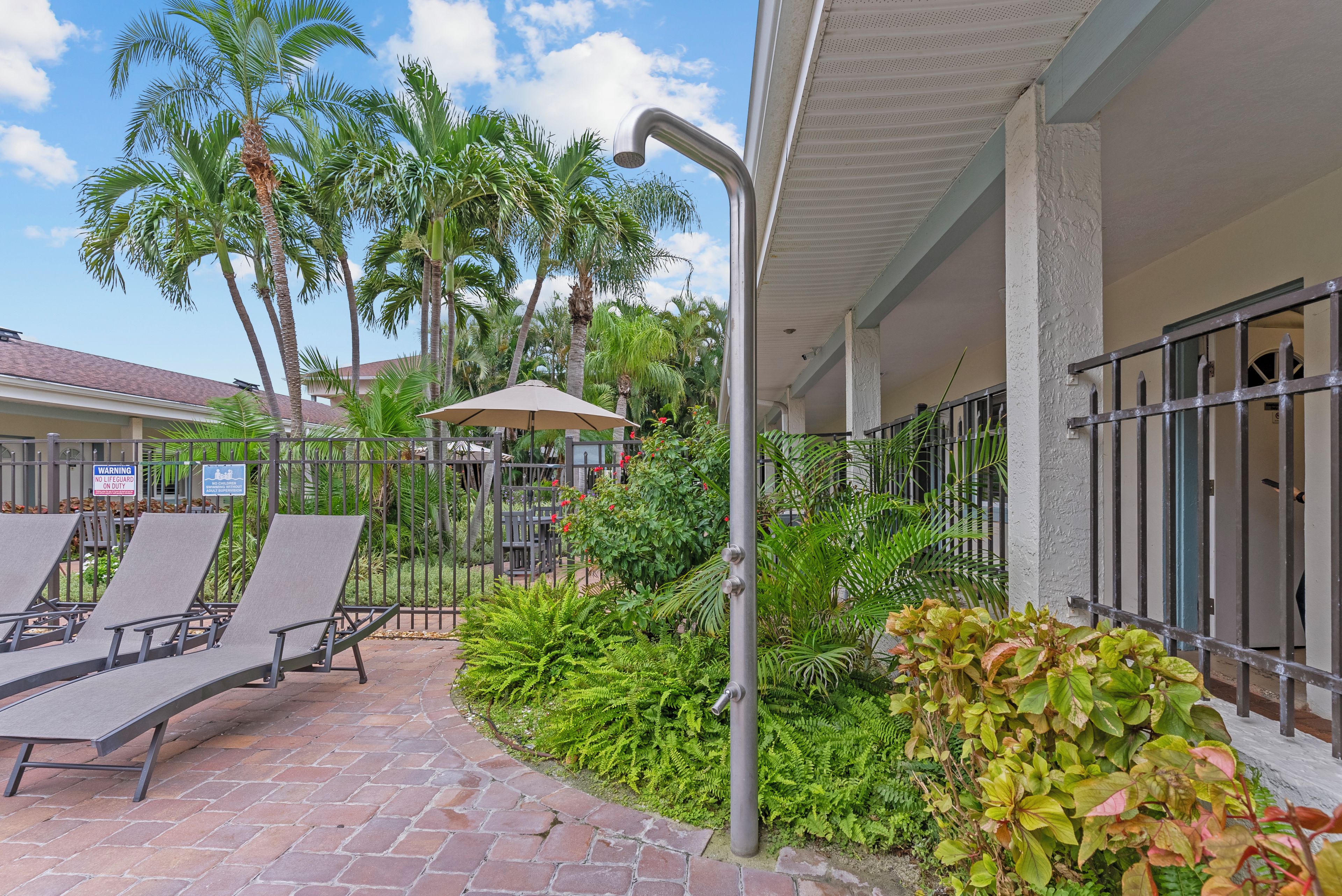 A courtyard with lounge chairs, a water feature, and tropical plants.