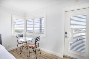 Una habitación con una mesa de comedor y sillas, una puerta con ventana y vistas al exterior.