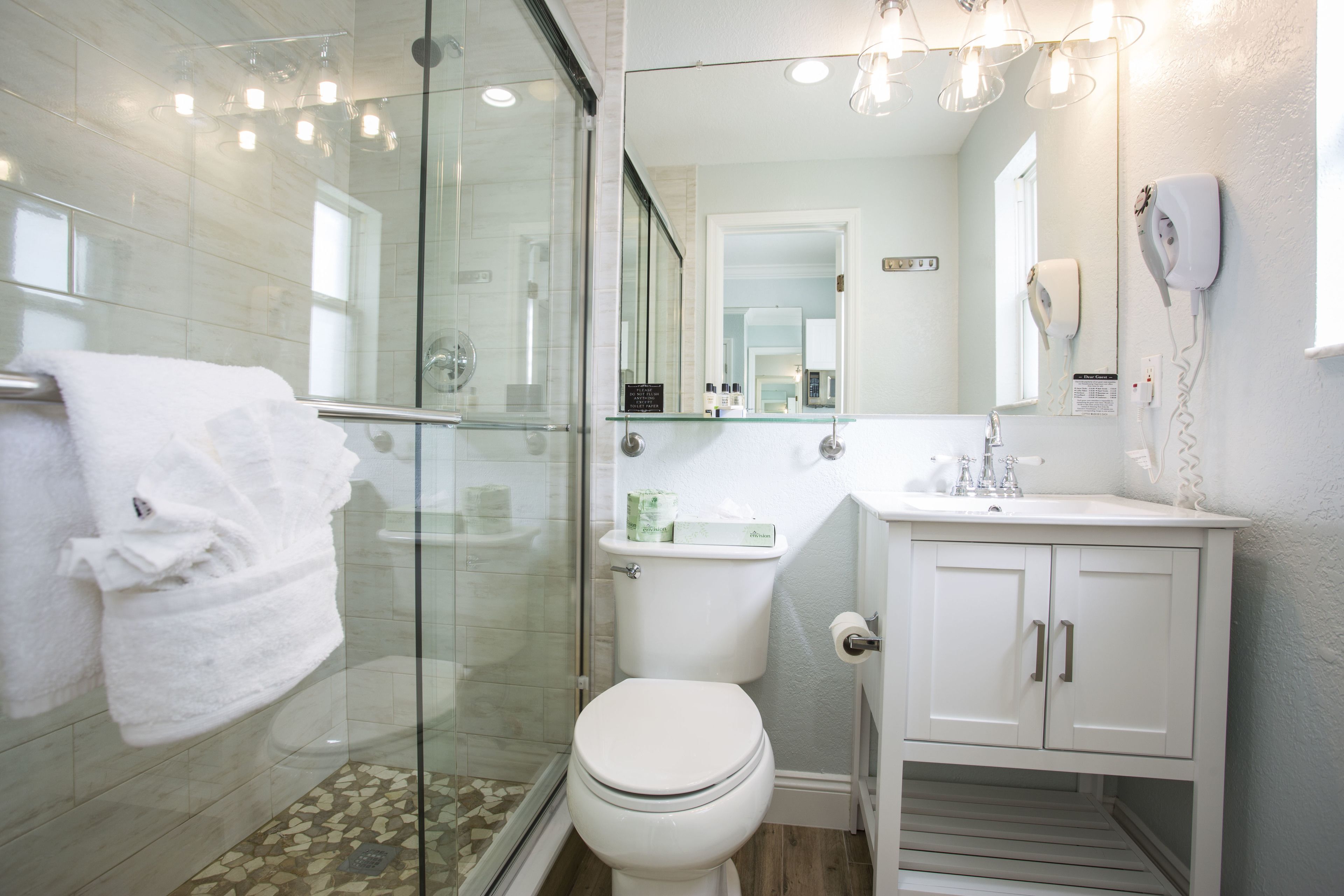 A modern bathroom with a glass shower enclosure, a toilet, and a vanity with a mirror.