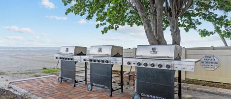 A barbecue grill setup with a view of the beach and ocean.