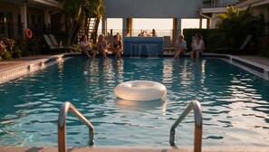 A swimming pool with a floating ring, lounge chairs, and a view of the sea. - Hotel Sol (Redington Shores)