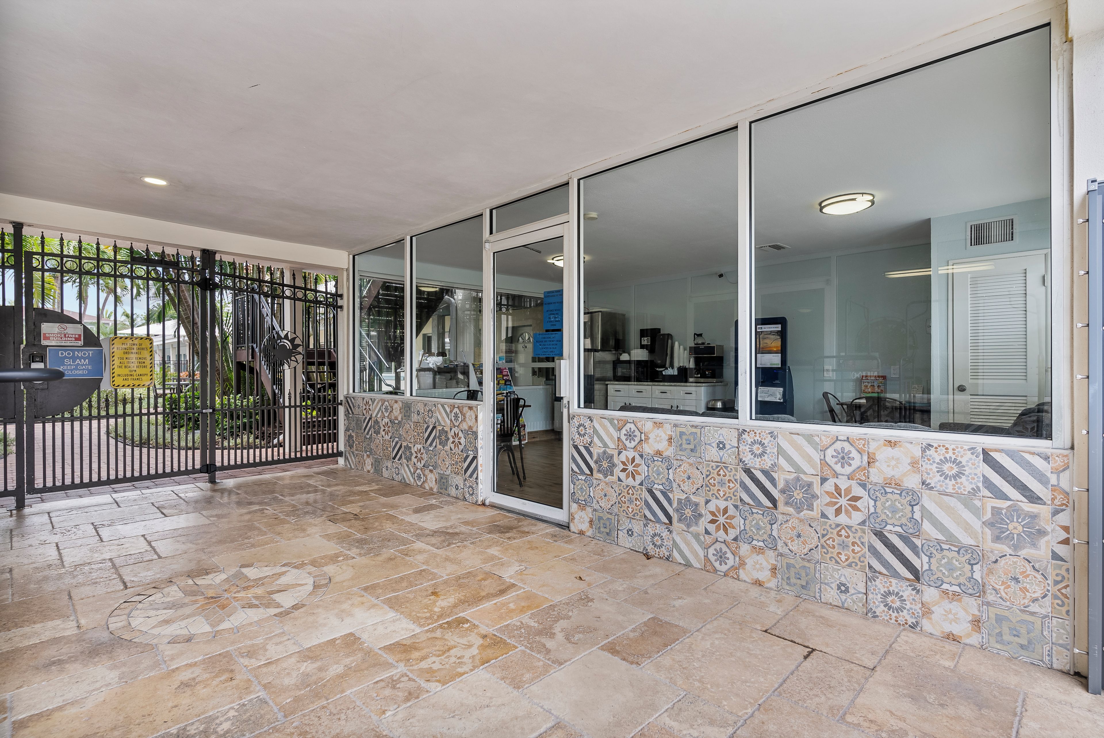 A reception area with a tiled floor, a glass door entrance, and a metal gate.