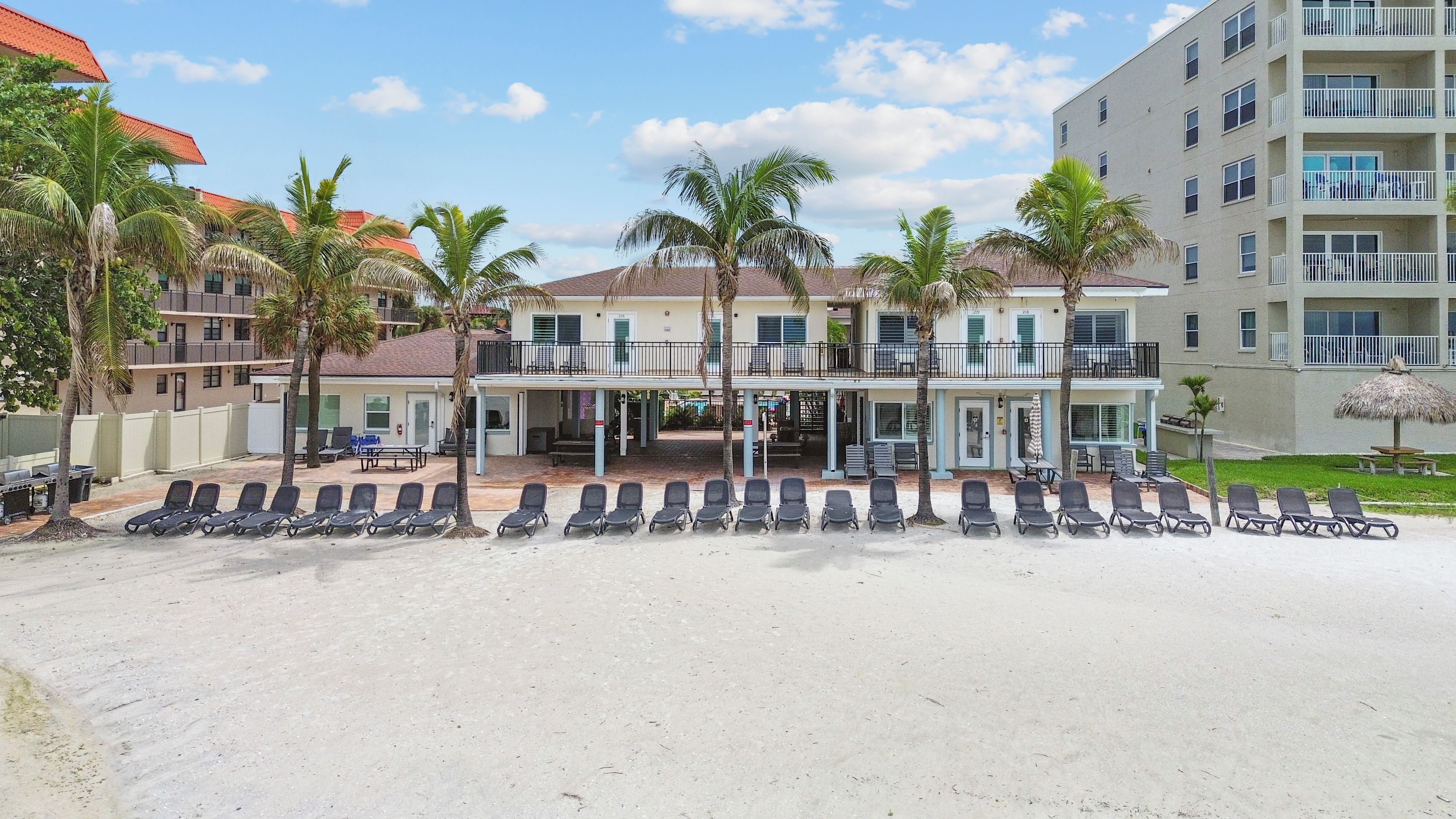 A beachfront hotel with multiple balconies, sun loungers, and palm trees.