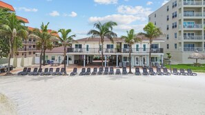 A beachfront hotel with multiple balconies, sun loungers, and palm trees. - Hotel Sol (Redington Shores)